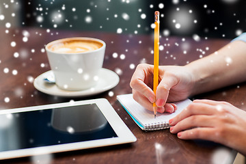 Image showing woman with tablet pc writing to notebook