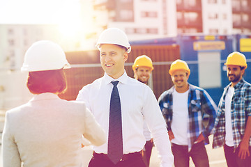 Image showing group of smiling builders in hardhats outdoors