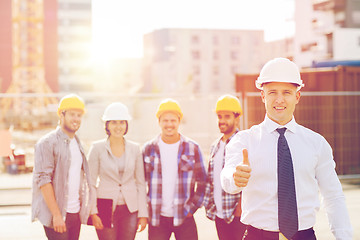 Image showing group of smiling builders in hardhats outdoors