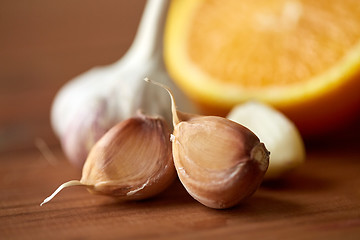 Image showing close up of garlic and orange on wooden table