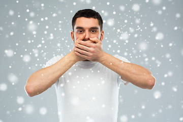 Image showing man in white t-shirt covering his mouth with hands