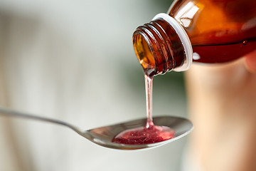 Image showing medication or antipyretic syrup and spoon