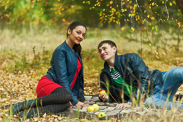 Image showing Young romantic couple sits on plaid. Autumn picnic