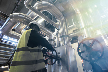 Image showing factory worker turning valve