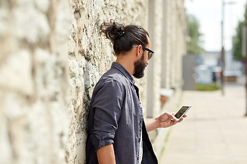 Image showing close up of man with smartphone at stone wall
