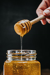 Image showing Person dipping honey stick in 