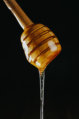 Image showing Person dipping honey stick in