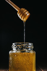 Image showing Person dipping honey stick in