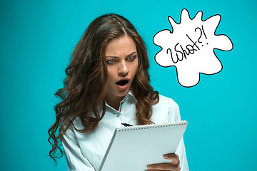 Image showing Surprised young business woman with pen and tablet for notes on blue background