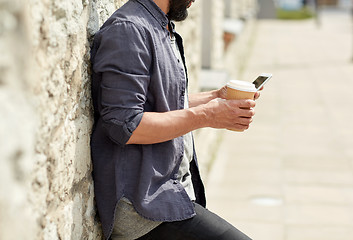 Image showing man with smartphone drinking coffee on city street