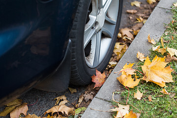 Image showing close up of car wheel and autumn leaves