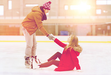 Image showing man helping women to rise up on skating rink