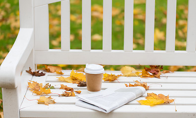 Image showing newspaper and coffee cup on bench in autumn park