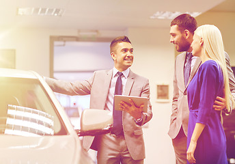 Image showing happy couple with car dealer in auto show or salon