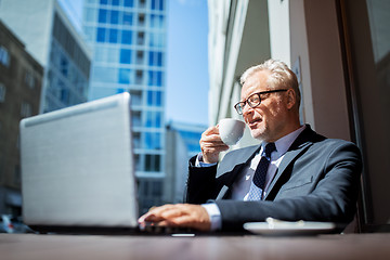 Image showing senior businessman with laptop drinking coffee