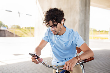 Image showing man with smartphone and earphones on bicycle