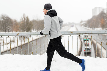 Image showing man running along snow covered winter bridge road