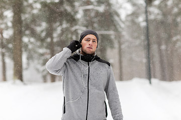 Image showing sports man with earphones in winter forest