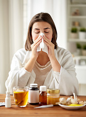 Image showing sick woman with medicine blowing nose to wipe