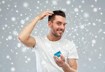 Image showing happy young man styling his hair with wax or gel