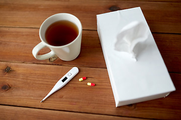 Image showing cup of tea, paper wipes and thermometer with pills