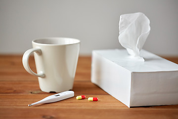 Image showing cup of tea, paper wipes and thermometer with pills