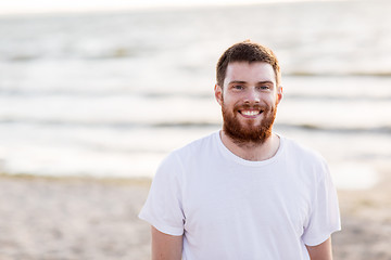 Image showing happy smiling young man with red beard on beach