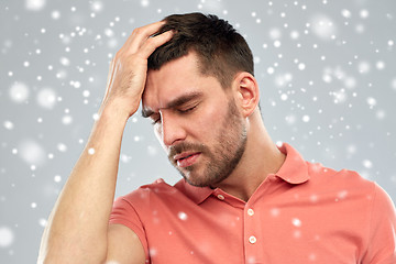 Image showing unhappy man suffering from head ache over snow