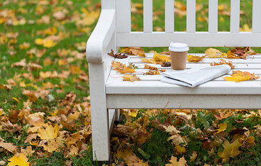 Image showing newspaper and coffee cup on bench in autumn park