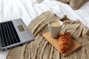 Image showing laptop, coffee and croissant on bed at cozy home