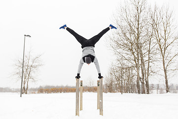 Image showing young man exercising on parallel bars in winter