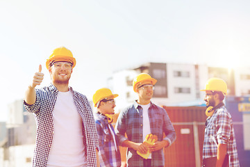 Image showing group of smiling builders in hardhats outdoors