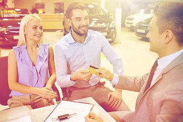 Image showing happy couple with car dealer in auto show or salon