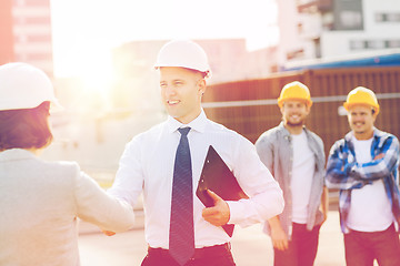 Image showing group of smiling builders in hardhats outdoors