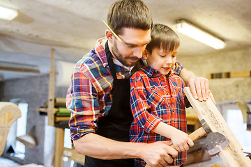 Image showing father and son with ax and wood plank at workshop