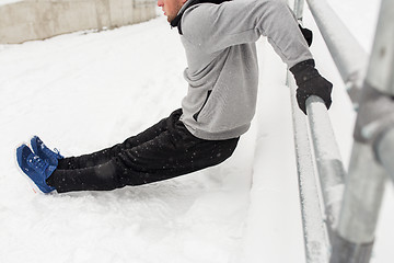 Image showing sports man doing triceps dips at fence in winter