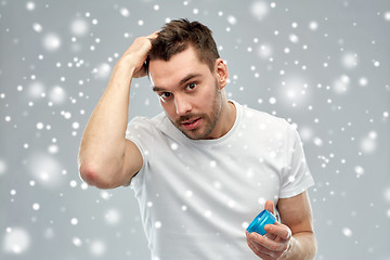 Image showing happy young man styling his hair with wax or gel