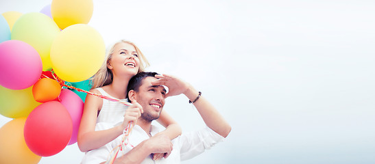 Image showing couple with colorful balloons at seaside