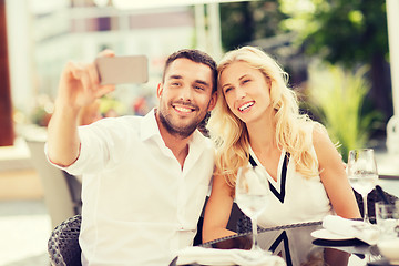 Image showing happy couple taking selfie with smatphone at cafe