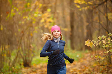 Image showing Young female athlete in sports suit running in autumn park
