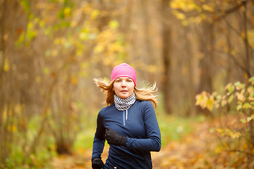 Image showing Young blond woman athlete running in forest on autumn day