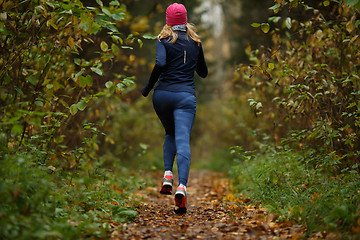 Image showing Young woman runs among trees