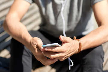 Image showing close up of man with smartphone and earphones wire