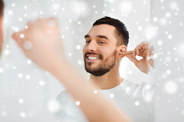 Image showing man cleaning ear with cotton swab at bathroom