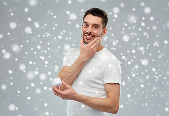 Image showing happy young man with cream jar over snow