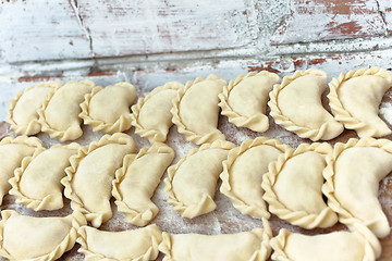 Image showing Dumplings on the wooden board near break wall outdoors