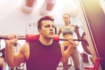 Image showing man and woman with barbell flexing muscles in gym