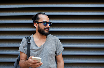 Image showing man with backpack texting on smartphone in city