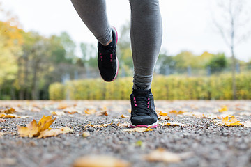 Image showing close up of young woman running in autumn park