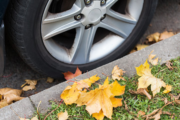 Image showing close up of car wheel and autumn leaves